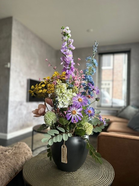 Schwarze breite Vase mit künstlichen Blumen in verschiedenen Farben